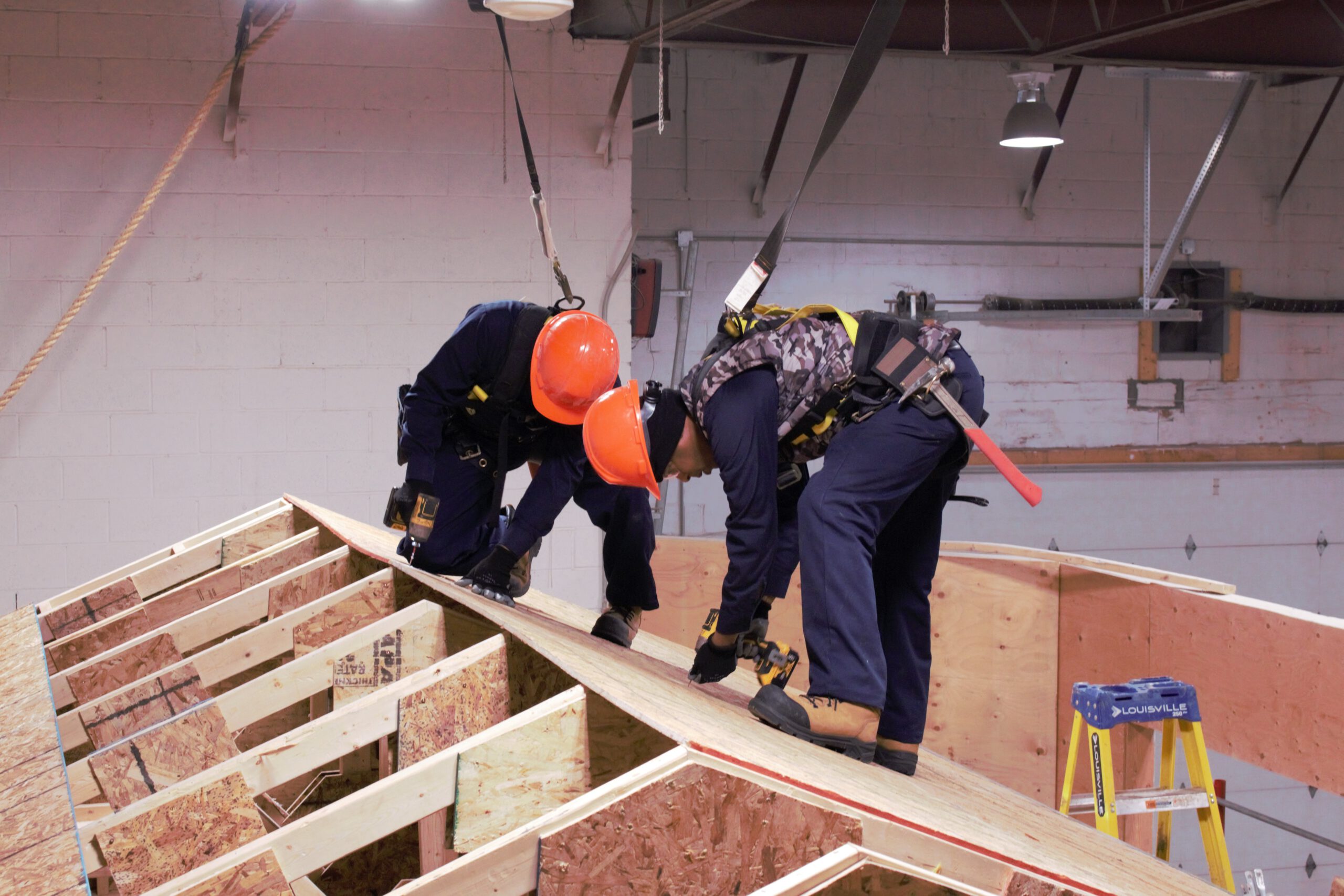 construction students learn to safely create a roof on a house
