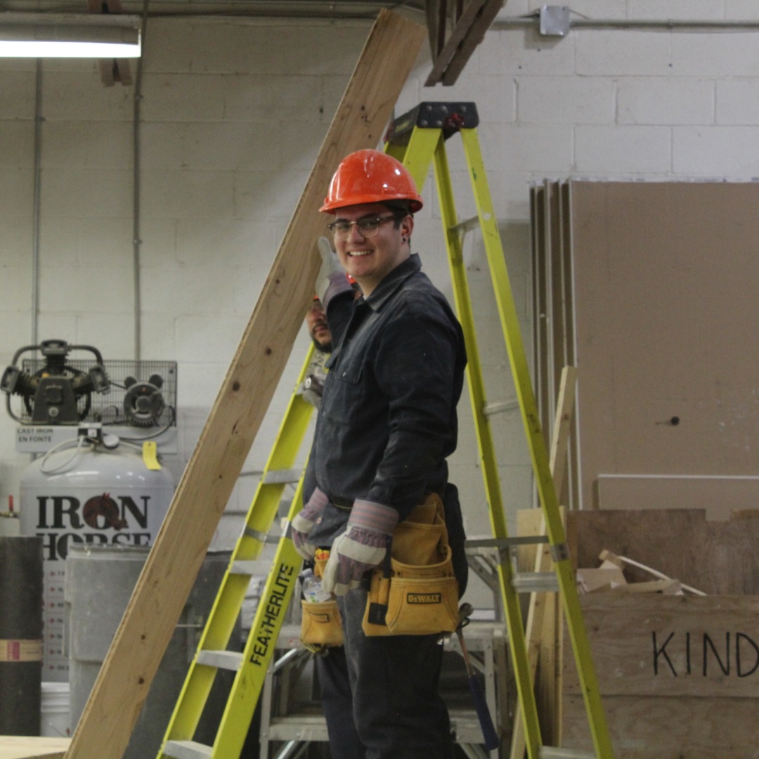 CTTstudent-ladder a CTT Student at a ladder in the work bay