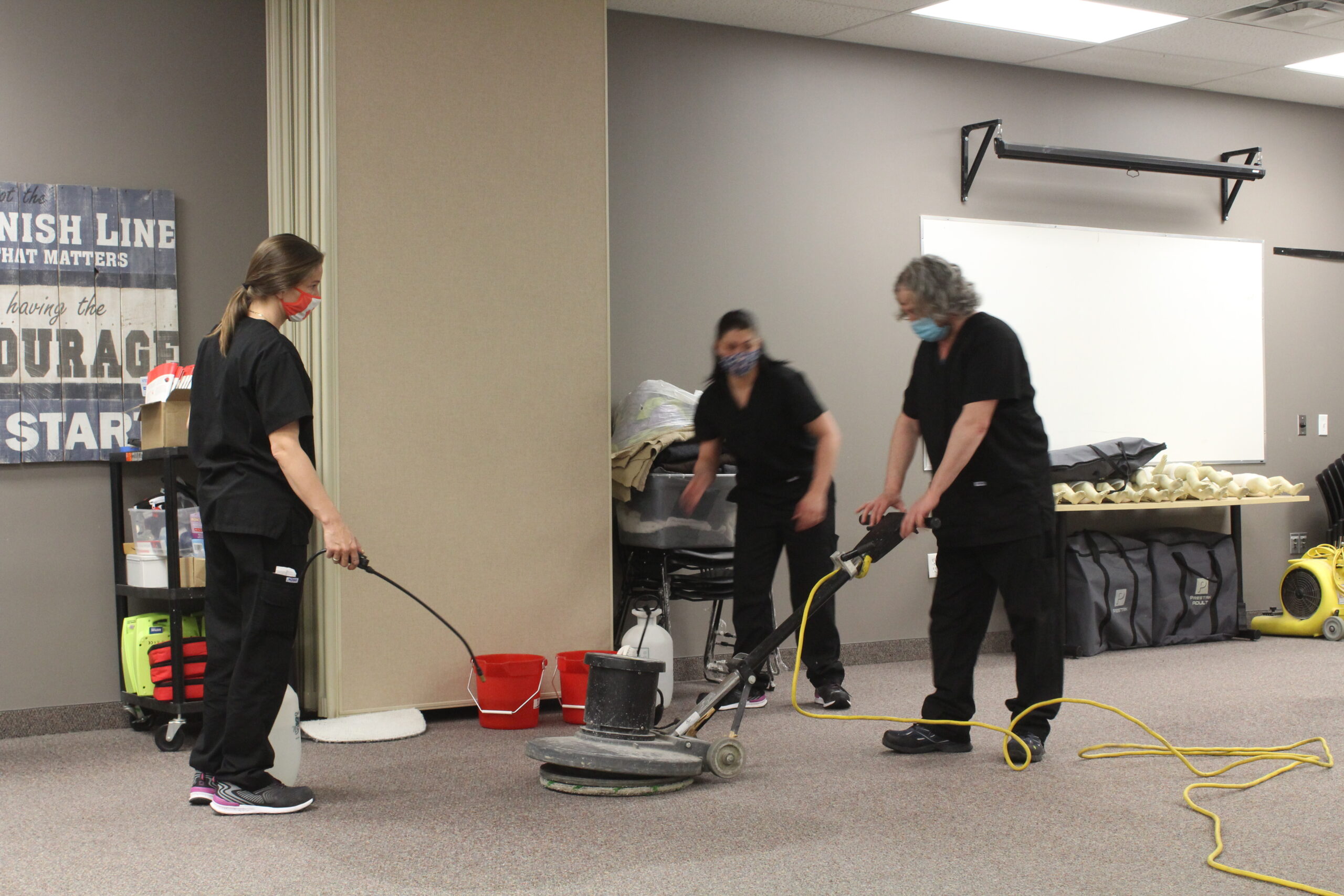 three students learn maintenance tasks at Pathways with floor buffers and cleaners