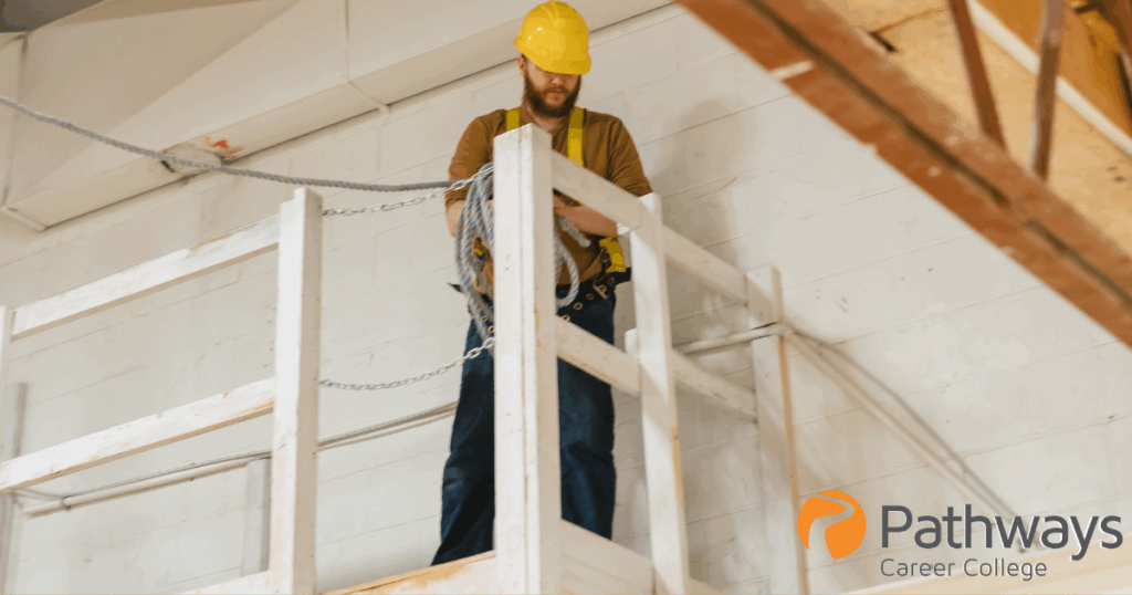 Tyler, facilitator at Pathways Career College, surveys the heights location while safely rigged for working at heights in a white fenced area