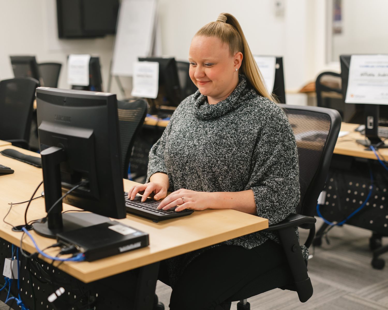 ACT student smiles as she reviews her keyboarding skills at the computer