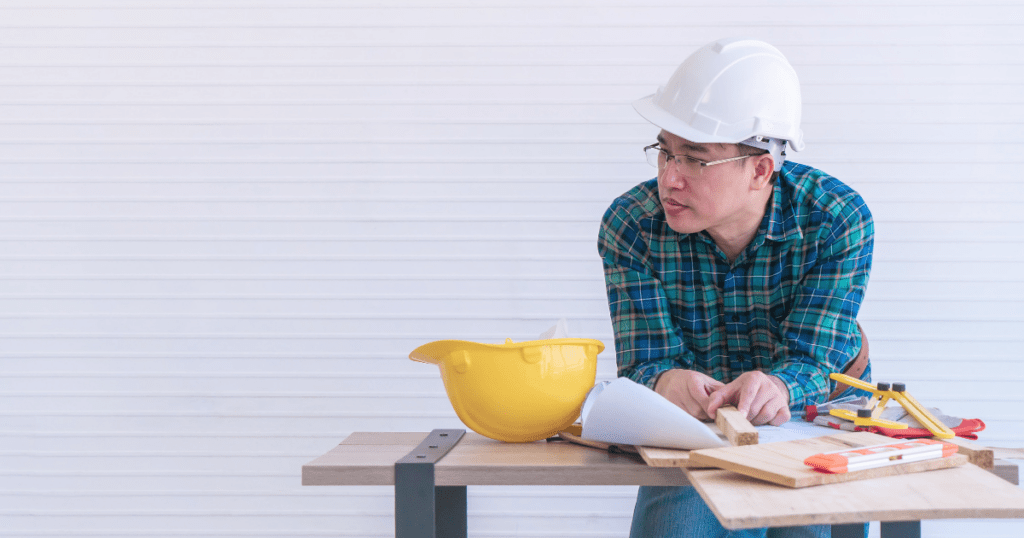 constructionworkerthinking | Pathways Career College a man in construction outfit standing at a table with tools, using what he learned from microlearning