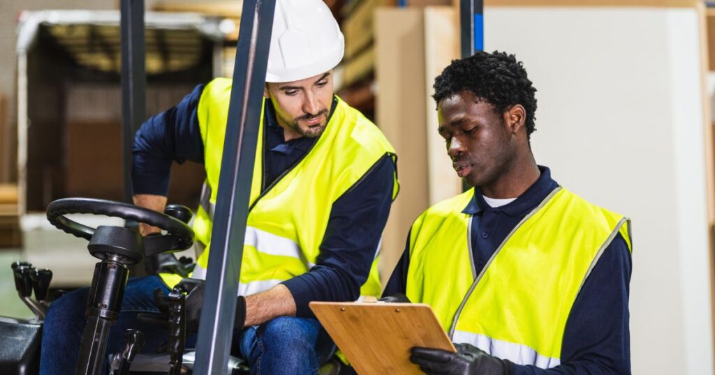 two workers help each other with learning to drive a forklift in their skills training