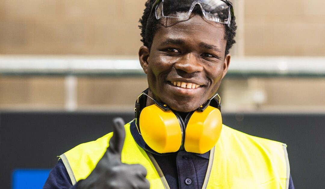a happy worker in a security vest and ear protection
